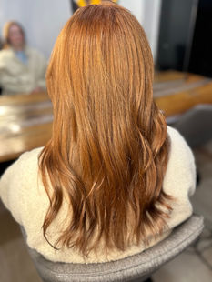 Long wavy orange hair color by a stylist