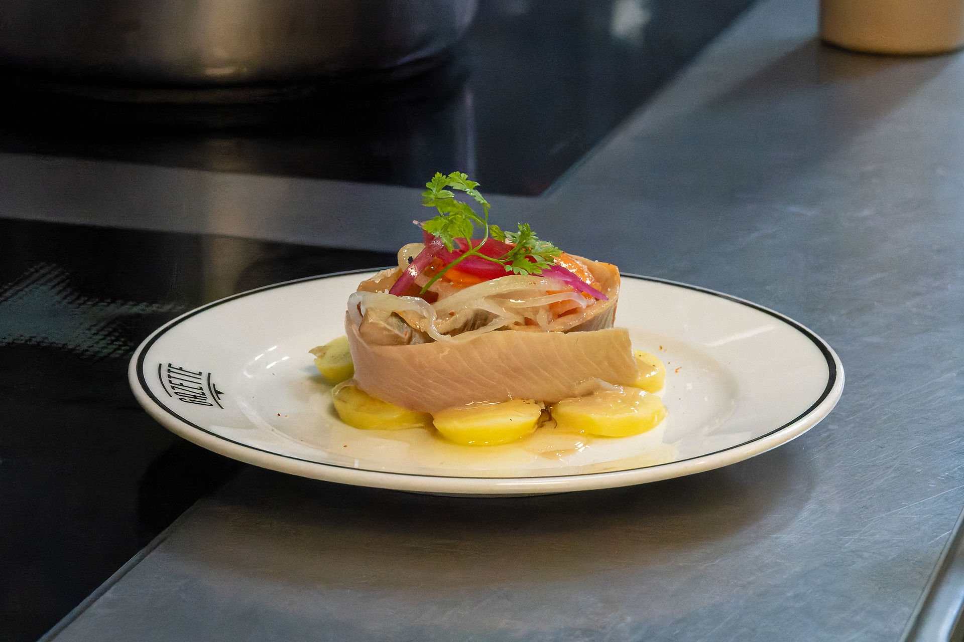 Filet de harengs sur pommes à l'huile, plat typique du restaurant La Gazette de Batignolles, présenté avec soin en cuisine.