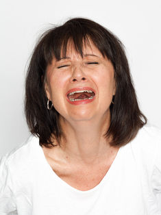 Photographie de type pola réalisée en studio sur fond blanc. Nathalie Chaban, modèle et comédienne, est photographiée en plan serré de face, avec une expression de tristesse contenue. Ce portrait brut et expressif, sans retouche de peau, met en valeur la capacité d’interprétation émotionnelle du modèle. L’image respecte les standards des photos de casting utilisées par les agences et directeurs de casting.