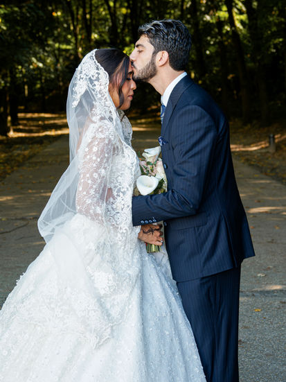 Le marié Omer dépose un baiser sur le front de Syrine, sa femme, lors d’une séance photo de couple après leur mariage civil, dans un moment empreint d’amour et de complicité.