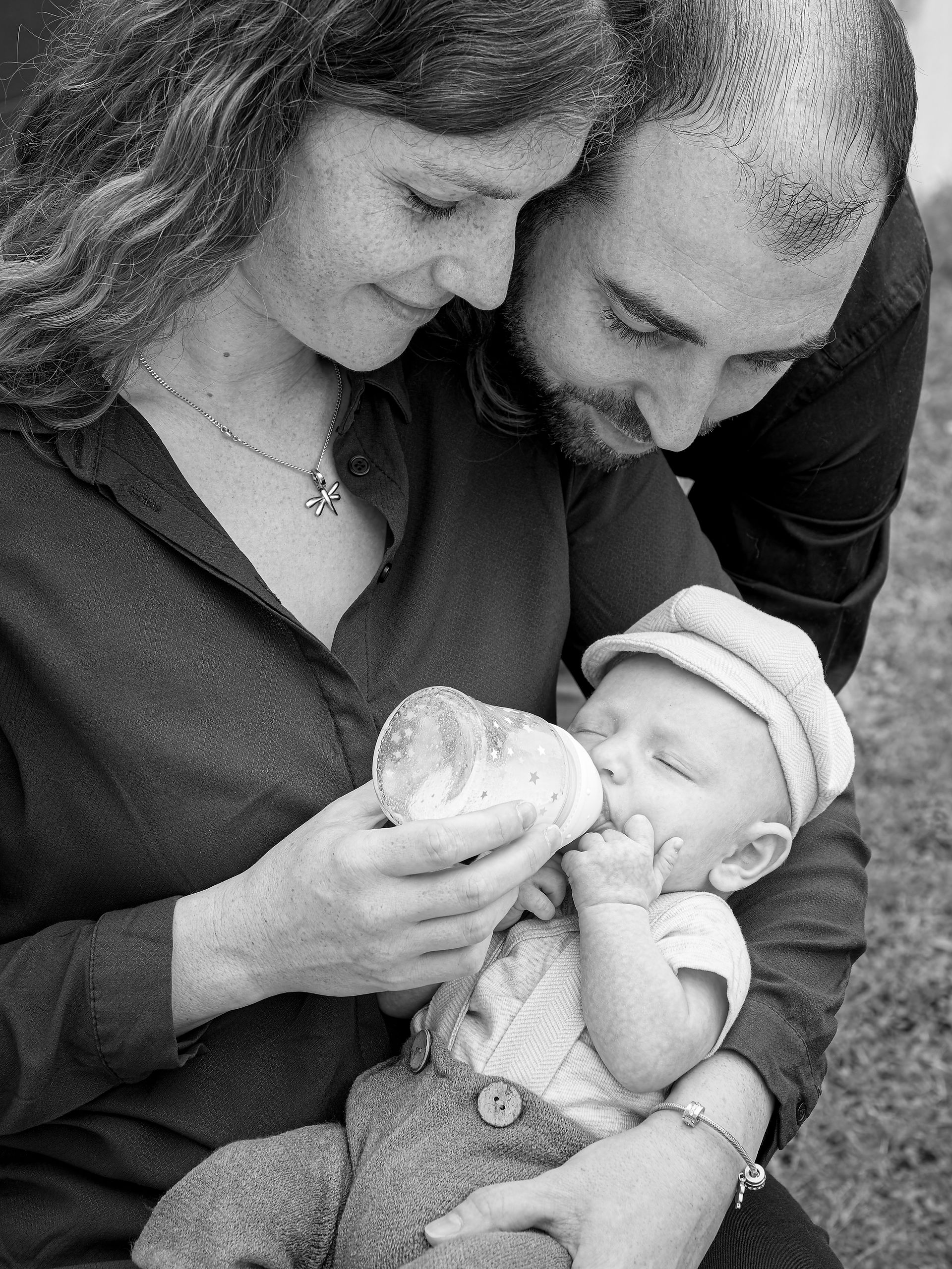 Photo en noir et blanc d’un moment tendre où les parents donnent le biberon à leur bébé, capturé lors d’une séance photo famille en région parisienne. L’image met en valeur la complicité, la bienveillance et le lien familial. Photographe nouveau-né à Gentilly, spécialisée dans les portraits naturels et les souvenirs authentiques des premiers mois de bébé.