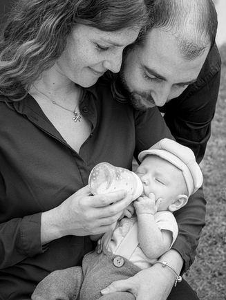 Photo en noir et blanc d’un moment tendre où les parents donnent le biberon à leur bébé, capturé lors d’une séance photo famille en région parisienne. L’image met en valeur la complicité, la bienveillance et le lien familial. Photographe nouveau-né à Gentilly, spécialisée dans les portraits naturels et les souvenirs authentiques des premiers mois de bébé.