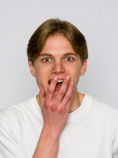 Portrait studio d’un comédien exprimant la surprise, main devant la bouche, regard caméra sur fond neutre. Photo professionnelle réalisée par le studio Colombe Photographie, spécialisé dans les books comédiens et portraits d’acteurs à Gentilly et en région parisienne. Idéal pour casting, agences artistiques et profils professionnels.