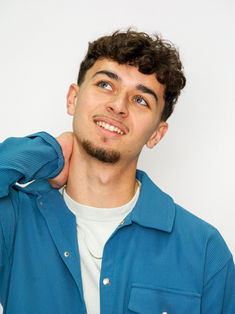 Portrait expressif de mannequin homme réalisé en studio avec fond bleu uniforme et lumière douce. Le regard dirigé vers le haut apporte une dimension émotionnelle et artistique, parfaite pour un book comédien. Idéal pour se démarquer lors de castings et valoriser la capacité d’interprétation du modèle.