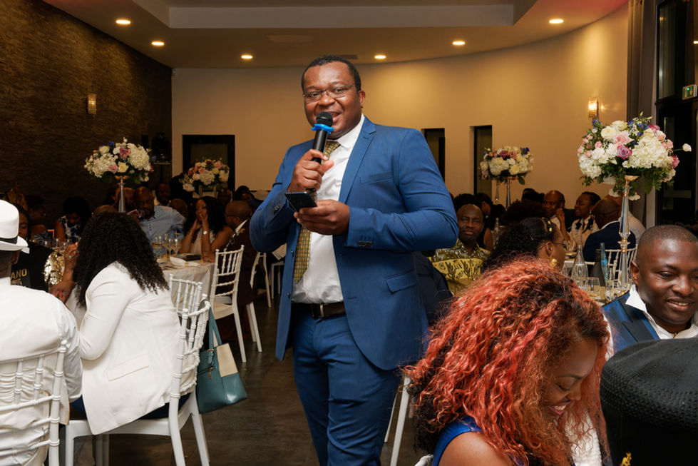 Photo du speaker animant la soirée d’anniversaire surprise des 50 ans d’Armel, micro en main, dans une salle décorée et remplie d’invités attentifs. Il intervient avec dynamisme et sourire pour ponctuer les moments forts du repas. Image réalisée par Colombe Photographie, photographe d’événements familiaux à Gentilly et en Île-de-France.