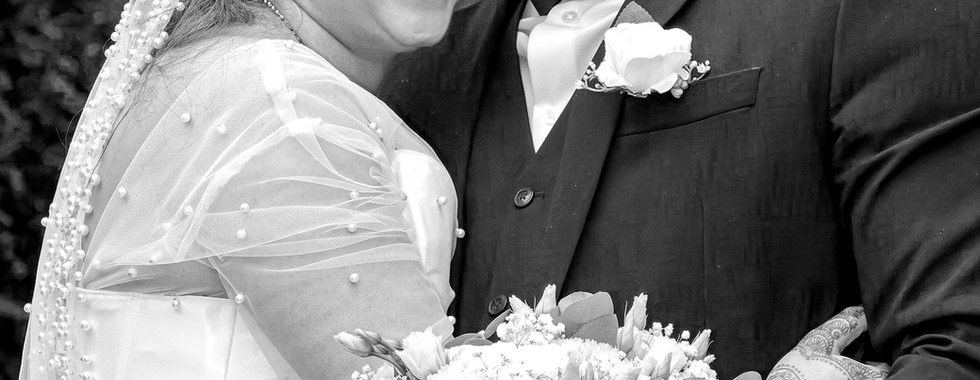 Photo de mariage en noir et blanc de Rania et Jordan partageant un moment complice, bouquet à la main. Image capturée par Colombe Photographie, photographe de mariage à Lyon.