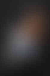 Portrait d’Ilhame, modèle atteinte de vitiligo, assise sur un tabouret en jean clair et débardeur marron, réalisée au studio Colombe Photographie à Gentilly. Photo de profil sur fond sombre, mettant en valeur les contrastes naturels de la peau et la douceur de l’expression. Shooting artistique autour du vitiligo, mené par une photographe spécialisée à Paris, valorisant la beauté singulière et la confiance en soi.