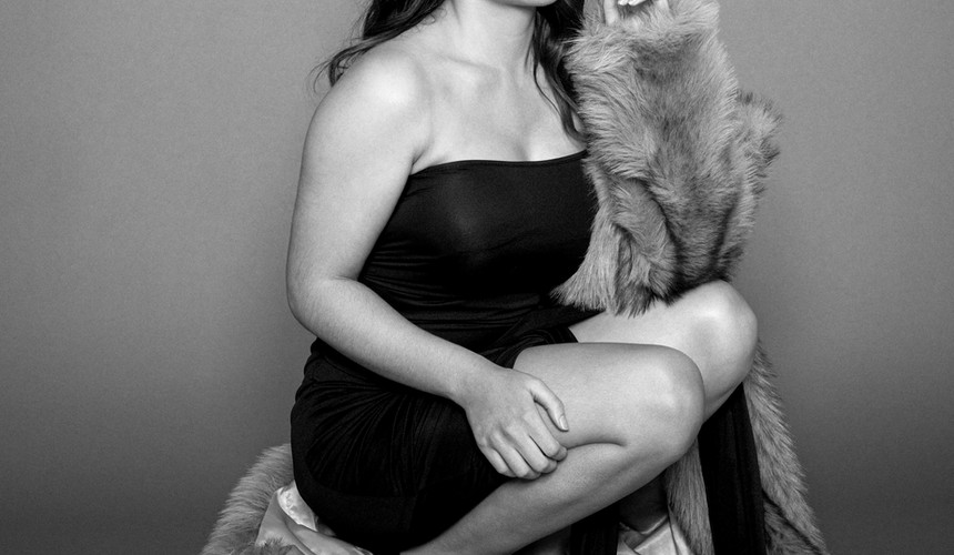 Portrait glamour réalisé par un photographe à Paris spécialisé dans les shootings mode et influenceuses. Séance photo studio avec robe noire, fausse fourrure et lumière éditoriale en région parisienne.
