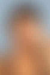 Portrait serré d’Ilhame, modèle atteinte de vitiligo, posant la main sur son visage devant un fond bleu clair. L’image met en avant les contrastes naturels de sa peau et la douceur de son regard. Réalisé au studio Colombe Photographie à Gentilly, ce shooting vitiligo artistique illustre l’estime de soi et la beauté unique des peaux atypiques. Photographe vitiligo à Paris et en région parisienne.