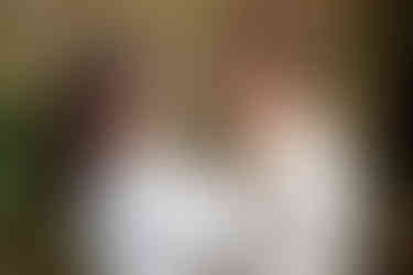 Photographie de couple prise après le mariage civil de Nathanaël et Hafsa à la mairie de Massy. La mariée enlace tendrement le visage de son mari tout en souriant, vêtue d’une superbe robe traditionnelle blanche aux broderies argentées. Ce portrait, capturé par Colombe Photographie, photographe de mariage à Gentilly et en Île-de-France, illustre avec émotion la complicité des jeunes mariés.