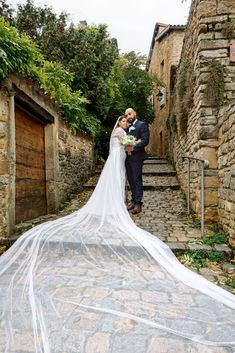 Photographie de mariage de Rania et Jordan enlacés dans une ruelle pavée, la mariée portant une longue traîne perlée. Photo réalisée par Colombe Photographie, photographe de mariage à Lyon.
