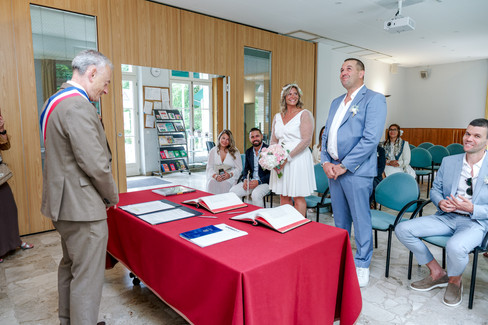 Photo du mariage civil de Mélanie et Stéphane à Conflans-Sainte-Honorine : les mariés se tiennent debout, émus et souriants, face à l’élu qui va célébrer leur union. Cette image capturée par Colombe Photographie, photographe de mariage en région parisienne, reflète l’authenticité et la joie d’une cérémonie intime et chaleureuse en Île-de-France.