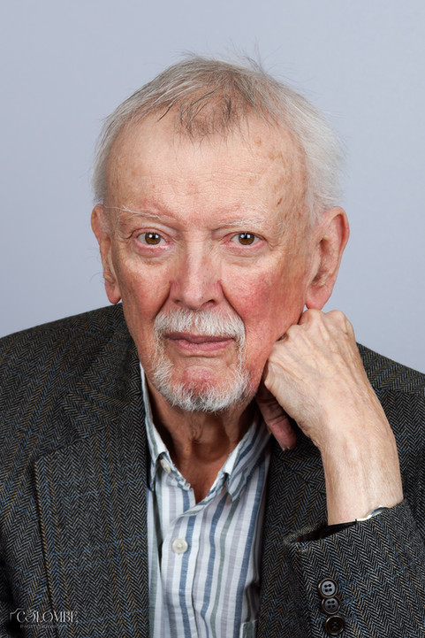 Portrait d'Etienne Schweisguth, auteur et sociologue, réalisé en studio. Photo professionnelle pour un livre, avec fond gris. Le visage de l'auteur est de face, avec un regard fixe et affirmé, le poing contre le visage. Il porte une chemise et une veste de costume, dégagent une image de sérieux et de réflexion.