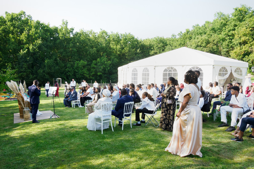 Vue d’ensemble de la cérémonie laïque du mariage de Malika et Richard à Guyancourt, organisée en extérieur sous tente, photographiée par Colombe Delons, photographe de mariage en Île-de-France.