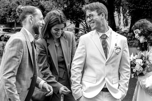 Photographie en noir et blanc prise lors du mariage civil de Nathanaël et Hafsa. Sur cette image captée à Gentilly en région parisienne, plusieurs invités échangent un moment complice et rieur avant le début de la cérémonie. Ce type de reportage naturel fait partie des prestations proposées par Colombe Photographie, photographe de mariage à Gentilly et en Île-de-France, spécialisée dans les images spontanées et authentiques.