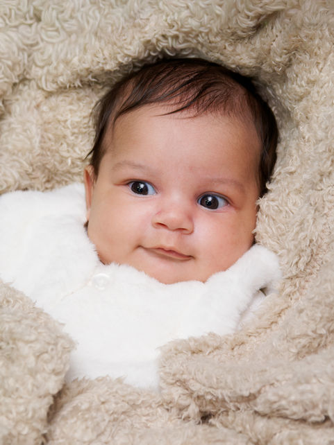 Portrait rapproché de naissance d’Alma, nouveau-né lové dans une couverture douce beige. Le bébé, vêtu de blanc, a les yeux grands ouverts, offrant un regard curieux et attendrissant. Ce cliché capture toute la délicatesse et l’authenticité des premiers instants de vie. Séance photo naissance réalisée en studio à Gentilly, aux portes de Paris. Photographe de nouveau-né et de famille à Paris et en Île-de-France, Colombe Photographie immortalise avec naturel et émotion les premiers mois des bébés pour leurs parents, Nidal et Olivier.