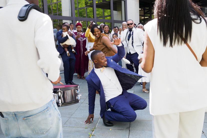 Invités dansant et célébrant la sortie des mariés Malika et Richard à la mairie de Guyancourt, en Île-de-France. Reportage mariage festif et lumineux réalisé par Colombe Delons, photographe de mariage en région parisienne, spécialisée dans les moments spontanés et authentiques.