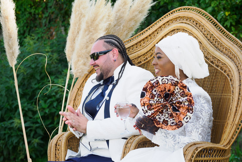 Portrait des mariés Malika et Richard assis sur un fauteuil en rotin lors de leur cérémonie laïque à Guyancourt, moment capturé par Colombe Delons, photographe de mariage en Île-de-France.