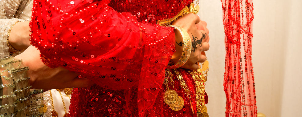 💬 Texte alternatif SEO : Mariée portant une robe traditionnelle rouge ornée de sequins et de bijoux dorés pendant une cérémonie kurde-tunisienne, photo de détails culturels réalisée par Colombe Photographie en région parisienne.