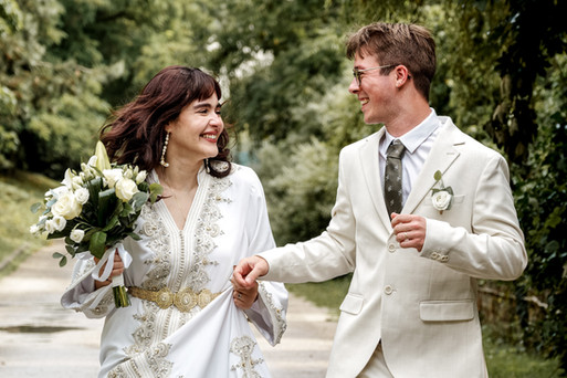 Portrait du couple Nathanaël et Hafsa lors de leur mariage civil à Massy, photographié par Colombe Photographie. Les jeunes mariés se tiennent par la main, souriants et habillés en blanc, dans une ambiance naturelle et joyeuse. Une scène tendre et spontanée capturée en Île-de-France par une photographe de mariage basée à Gentilly.