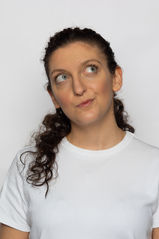 Pola de Cécile Aknin, réalisé en studio, portrait serré avec un sourire espiègle et une expression joyeuse, mettant en valeur une attitude ludique et pleine de malice.