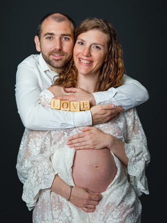 Séance photo grossesse en couple en studio à Gentilly, proche de Paris. Future maman avec ventre arrondi et couple complice tenant un mot “LOVE”. Portrait grossesse naturel et lumineux réalisé par un photographe grossesse en Île-de-France, idéal pour immortaliser l’attente d’un bébé en studio professionnel.