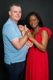 Photo de famille réalisée en studio à Gentilly, montrant les parents posant ensemble avec leur nouveau-né. Image colorée et élégante, mettant en lumière la complicité et la joie de cette jeune famille. Photographe nouveau-né et famille en région parisienne, proposant des séances en studio aux portes de Paris dans une ambiance douce et professionnelle.