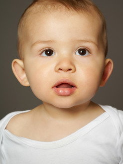 Portrait bébé en studio sur fond gris, regard expressif et lumière douce, réalisé par Colombe Photographie à Gentilly en Île-de-France. Shooting photo naissance et famille en région parisienne, idéal pour capturer des souvenirs naturels et authentiques. Studio photo spécialisé en portraits bébé et famille.