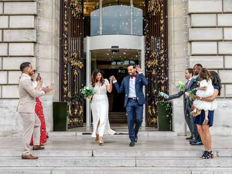 Chamima et Olivier sortent de la mairie de Levallois-Perret main dans la main après leur mariage civil, entourés de leurs proches. Une pluie de bulles les accueille à la sortie, dans une ambiance joyeuse et conviviale. Photo capturée par Colombe Photographie, photographe de mariage à Gentilly, spécialisée dans les reportages vivants et naturels en région parisienne.