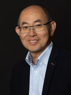 Portrait professionnel corporate sur fond noir. Ty, le modèle, regarde la caméra avec un regard affirmé et bienveillant. Portrait sobre et élégant, adapté à un usage CV ou LinkedIn.