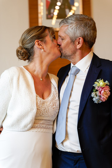 Xavier et Camille échangent un baiser juste après leur mariage civil à la mairie du 17e arrondissement de Paris. Photographie capturée par Henock pour le studio Colombe Photographie, photographe de mariage civil à Paris et en région parisienne.