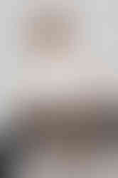 A Polaroid shot by Colombe Delons, a portrait photographer based in Gentilly, near Paris, in her Colombe Photographie studio. Model Cécile Aknin sits on a chair, slightly off-center, with a neutral expression. She's wearing a white t-shirt and black jeans, embodying a style that's both natural and fashionable/editorial. This photo was taken against a white background, unretouched, offering an authentic and professional image for high-quality Polaroids.