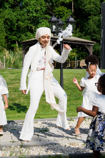 Photo d’une invitée dansant avec des enfants pendant la réception du mariage de Malika et Richard à Guyancourt, en Île-de-France. Reportage mariage joyeux et lumineux signé Colombe Delons, photographe de mariage en région parisienne.