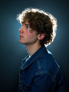 Portrait de profil réalisé en studio pour enrichir un book comédien professionnel à Paris. La lumière de contour souligne la ligne du visage et la coiffure, apportant une lecture différente du profil du comédien. Ce type de photo est souvent apprécié en complément des portraits face caméra dans un book artistique. Séance réalisée chez Colombe Photographie, studio photo à Paris spécialisé dans les portraits de comédiens.