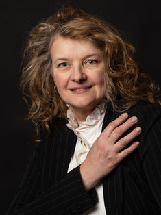 Nathalie, modèle rousse, chemise blanche et veste noire, regard direct vers la caméra.