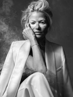 Alexia en costume blanc, maquillage pudré blanc, fumée créant un effet artistique, regard fixe vers l'objectif.