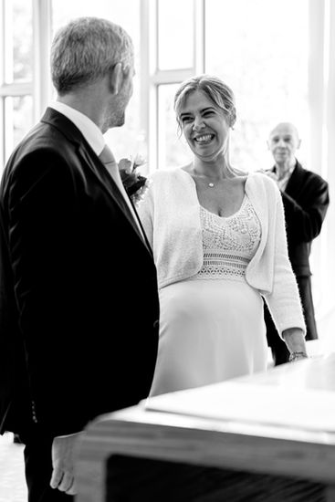 Photographie en noir et blanc de Xavier et Camille échangeant un rire complice lors de leur mariage civil à la mairie du 17e arrondissement de Paris. Image capturée par Henock pour le studio Colombe Photographie, photographe de mariage civil à Paris et en Île-de-France.