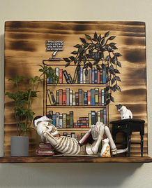 Handcrafted wood art featuring a skeleton reading among colorful books and playful cats beneath a vine, combining humor and intellect.