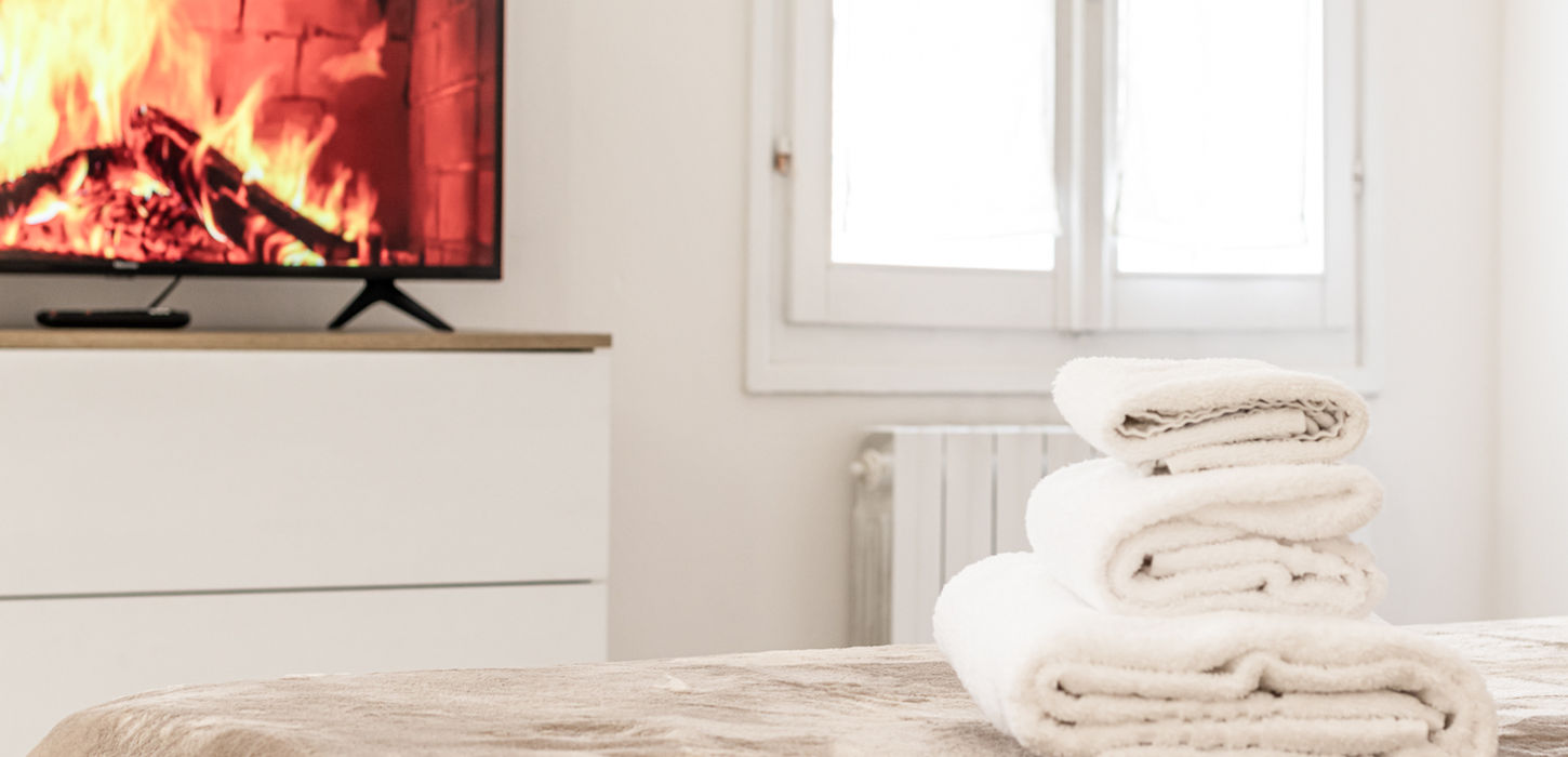 A stack of white towels on the bed, Casa Pico near a lit fireplace