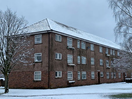 Block of flats covered in snow with bare trees in the foreground, South Lanarkshire, Scotland.