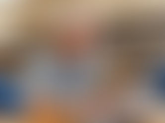 An older man with grey hair, wearing a t-shirt, sitting at a desk in the local library learning how to use a computer.