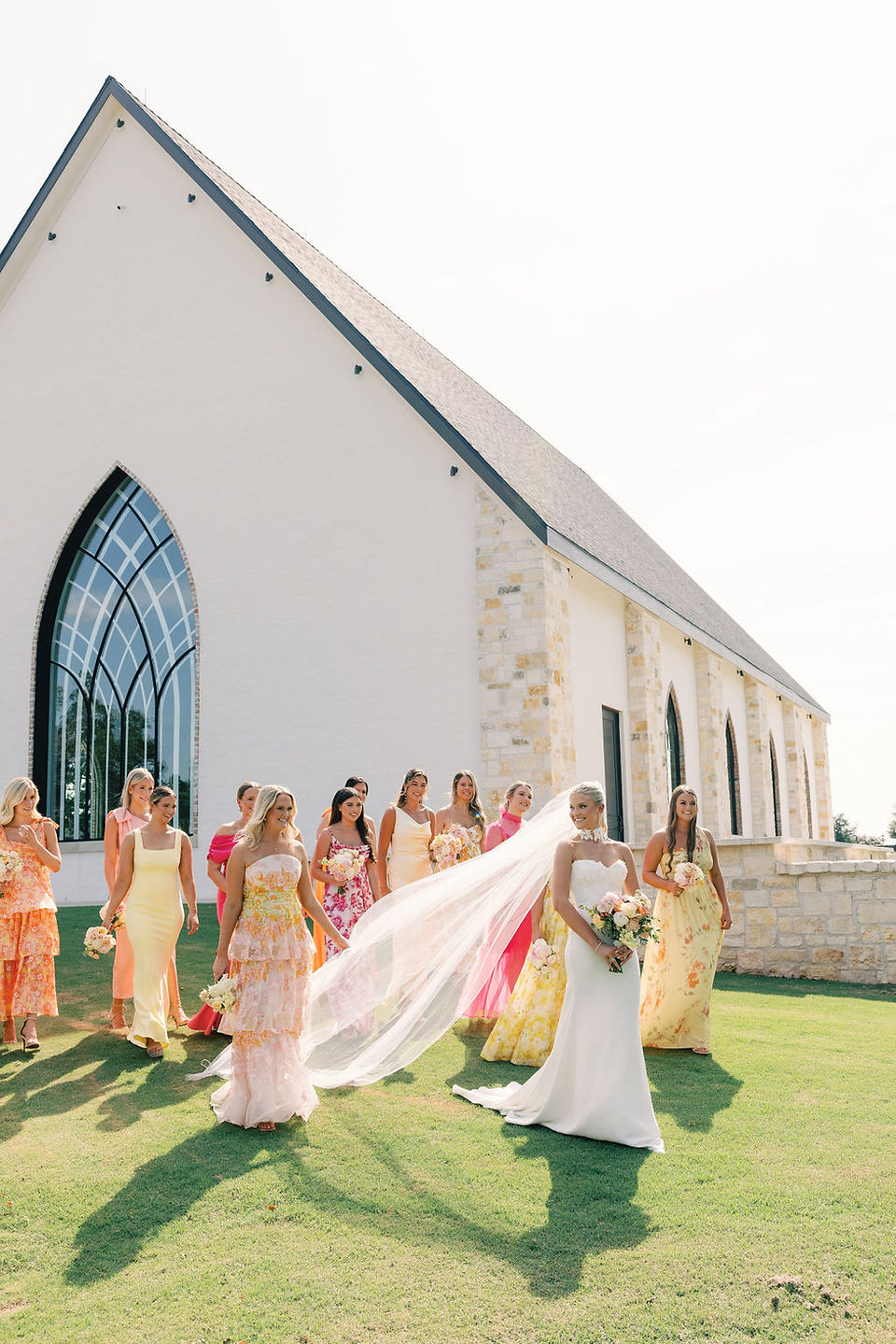 colorful bridesmaid dresses outside of wedding chapel on green grass