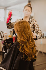 A woman spraying hair spray on another woman's hair