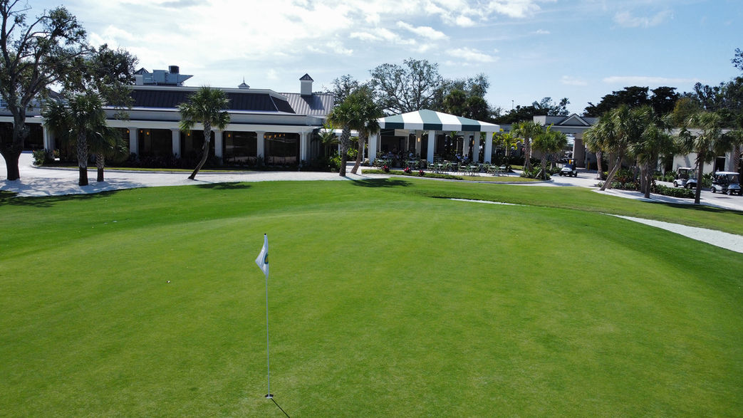 A putting green with the Boca Grove clubhouse in the background