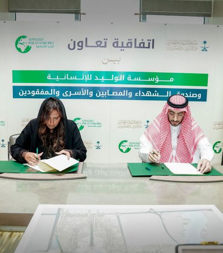 A man and a woman sign a cooperation agreement for the Alwaleed Philanthropies Foundation.