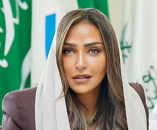 امرأة بشعر بني وحجاب أبيض، وأعلام سعودية في الخلفية