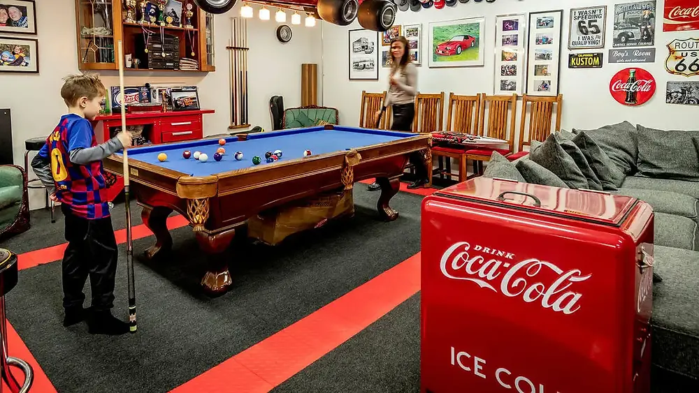 Child & adult playing billiards in transformed garage.