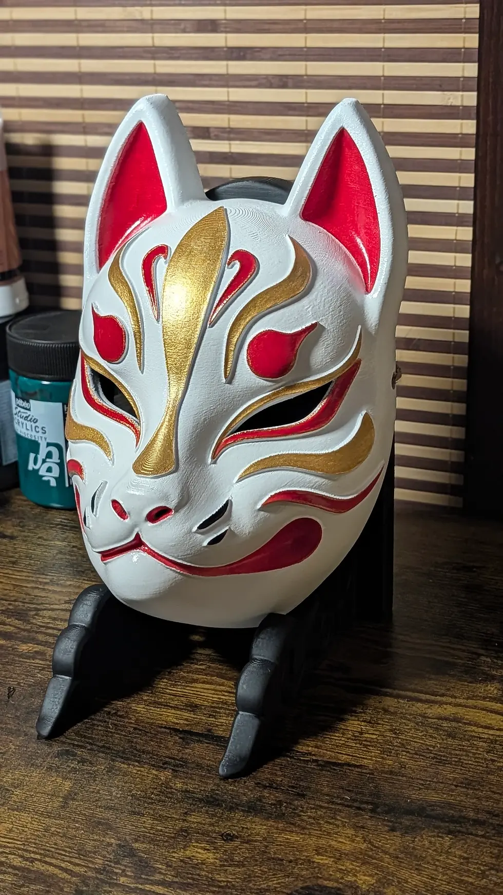 Miniature : Masque Kitsune blanc moderne sur stand, marquages or et rouge peints à la main, création Dai Yokai Bretagne France
