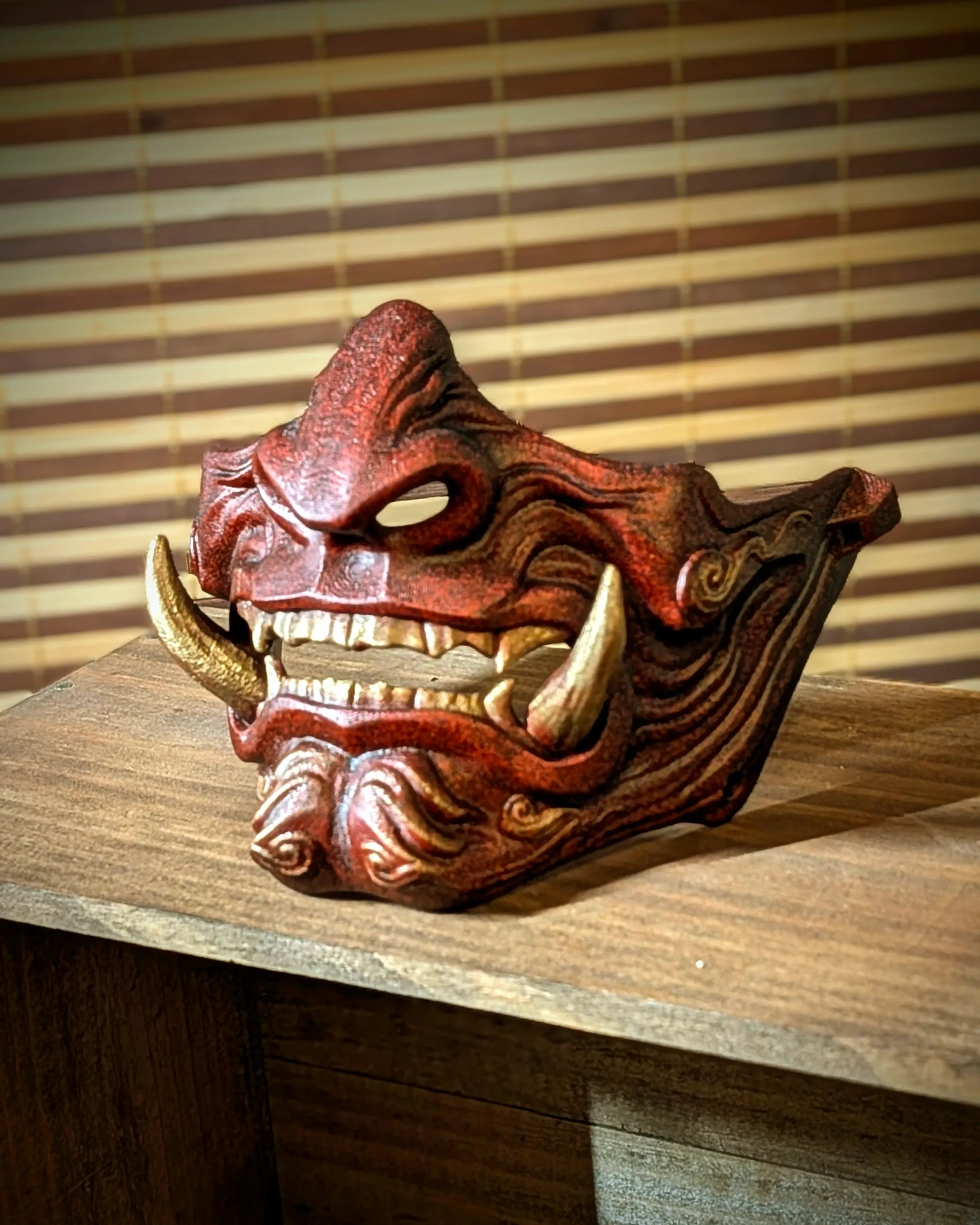 Handmade red Mempo Hannya half-mask in PETG by Dai Yokai, with gold fangs and an aged finish, in the style of a rōnin samurai