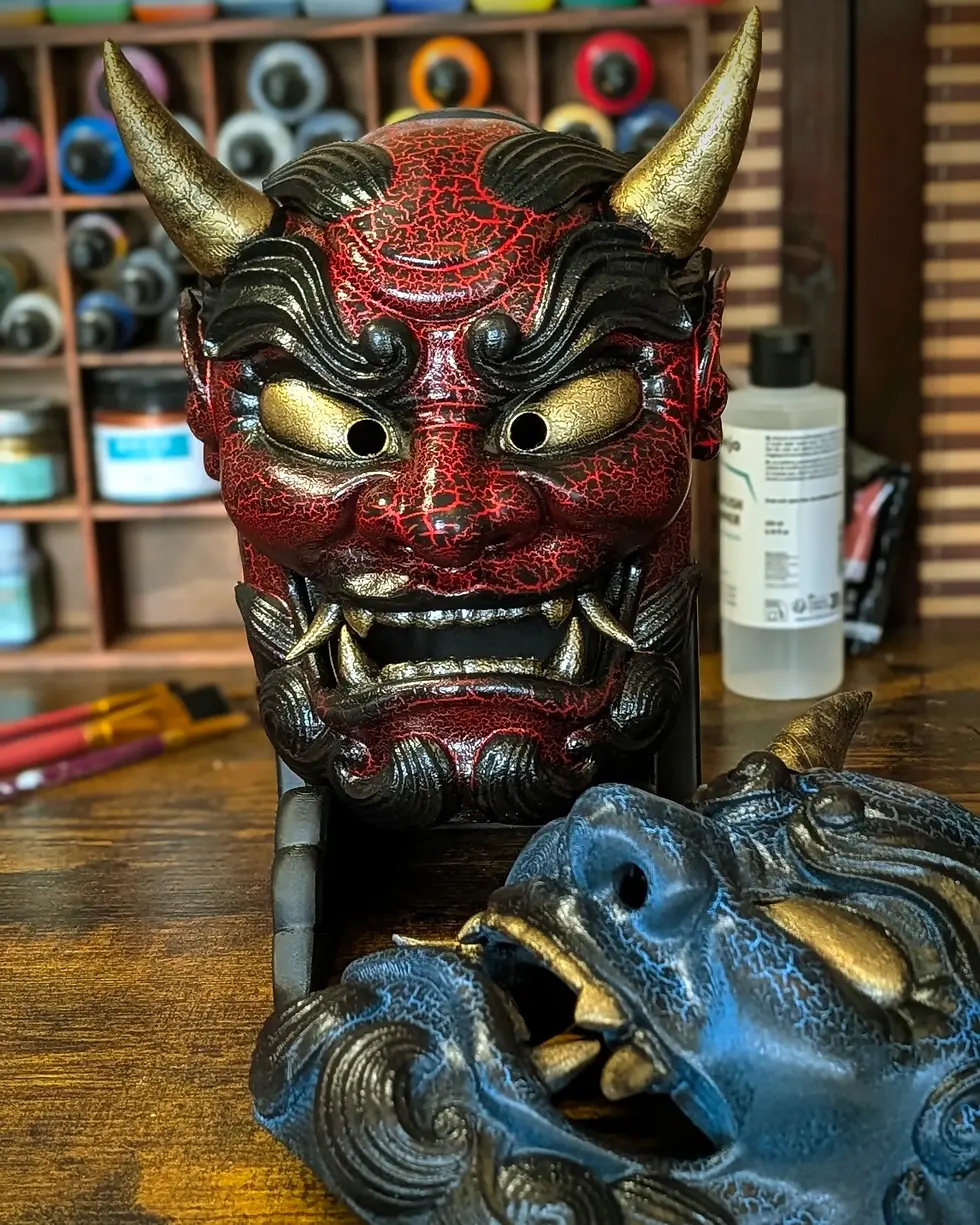 Masques Oni japonais artisanaux (Rouge et Bleu) sur l'établi de l'atelier Daiyokai, fabrication française